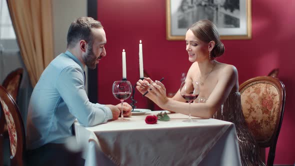 Couple Laughing Looking at Screen of Smartphone Together at Romantic Date