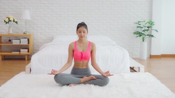 Attractive Asian woman practice yoga lotus pose to meditation in bedroom