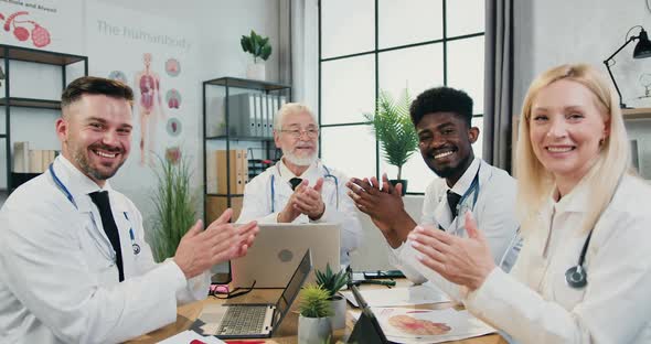 Medics Sitting at Boardroom Table and Clapping Hands After Successful Ending Joint meeting