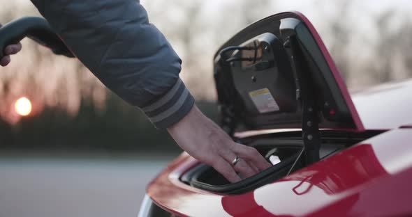 Male Hand Charging Electric Vehicle Closing the Lid of an Electrical Car After Charging