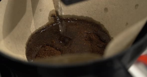 Filtered coffee brewing. Dripping hot water over ground coffee in paper filter. Slowmotion