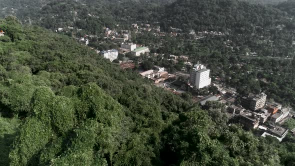 Aerial tilt shot reveals city surrounded by big hills.