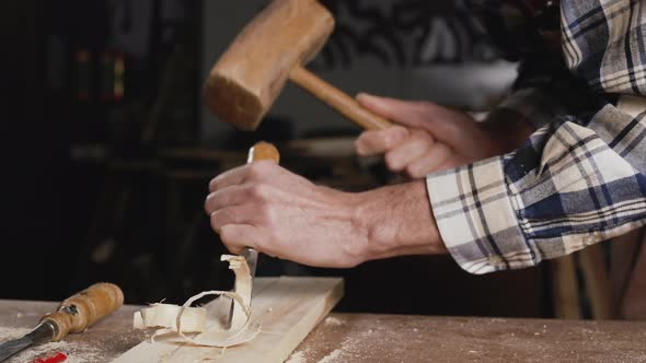 Skilled Carpenter Carving Wood with Hammer and Chisel