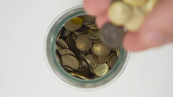 Caucasian Man Dropping Polish Currency Coins into a Jar