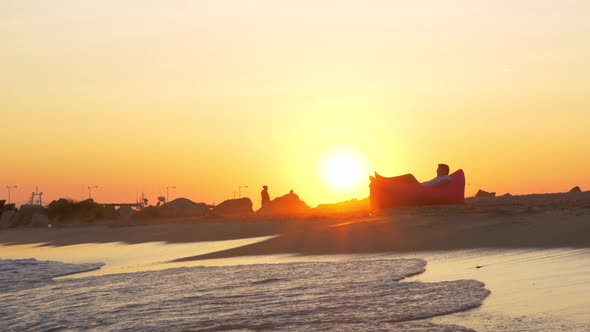 Sunset scene of man relaxing in inflatable sunbed at the seaside