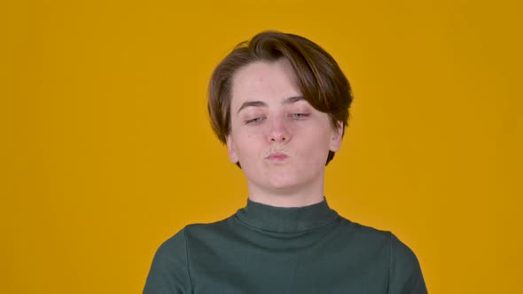 Cheerful Young girl thinking about something standing isolated on yellow studio background.