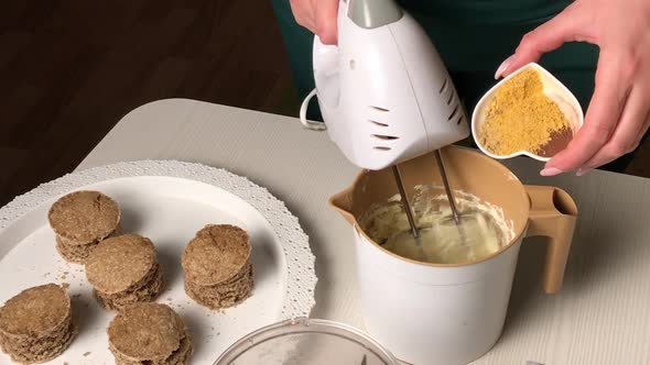 A Woman Makes A Sponge Cake With Butter Cream And Biscuit Crumbs. Adds Spices To The Cream.