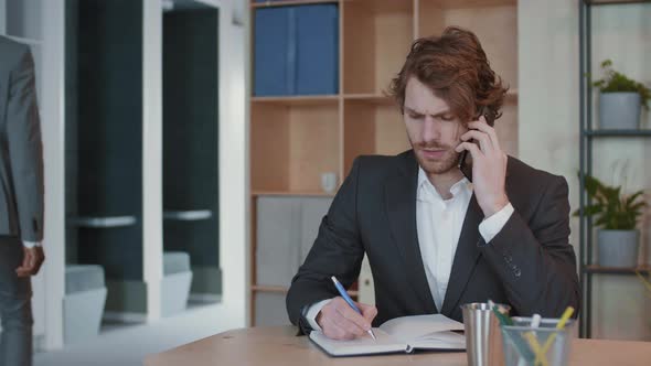 Businessman Talking on Phone while Working