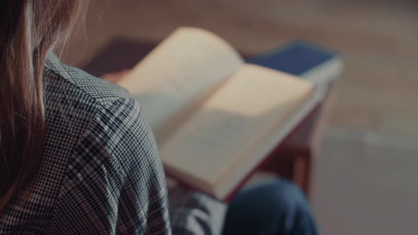 Young Caucasian Woman Flips Through the Pages and Gets Acquainted with the Contents of the Book