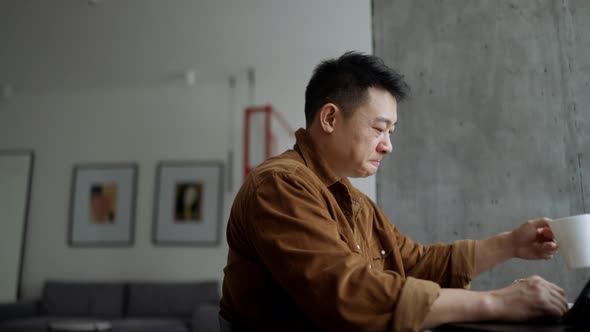 Handsome Asian man drinking coffee and eating