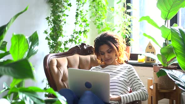 Woman Using Laptop Computer and Searching in Internet Sitting on Couch at Home Room Spbd