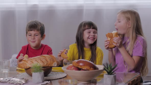 Carefree Childhood, Happy Boy and Smiling Girls Sitting at Sweet Table Eating Aromatic Pastries