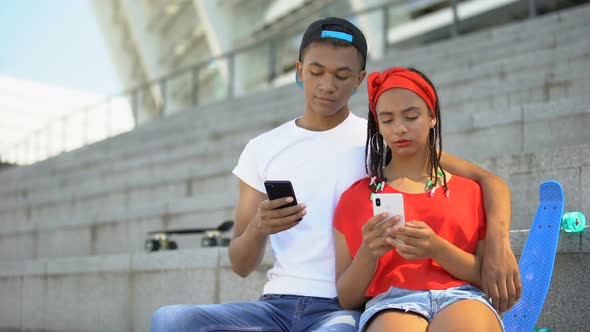 Teenagers Couple Spending Time Together Scrolling Social Networks on Smartphone