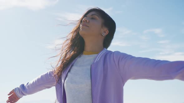 Mixed race woman with arms wide at the beach on sunny day