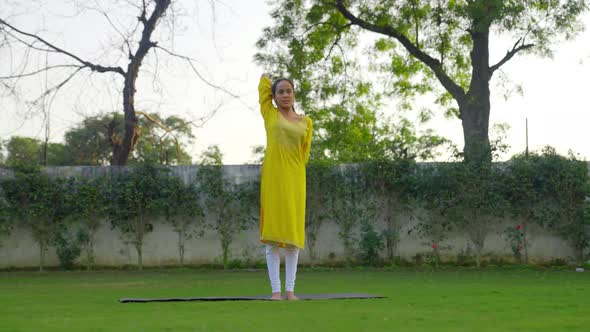 Cow face yoga pose or Gomukh asana is being done by an Indian woman in an Indian dress