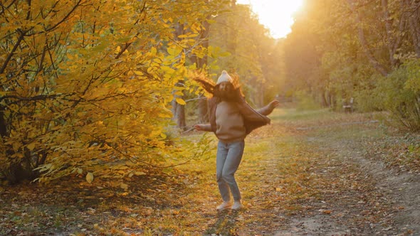 Young Happy Funny Cheerful Hispanic Girl Walking Outdoors in Autumn Park Spinning Jumping Enjoying