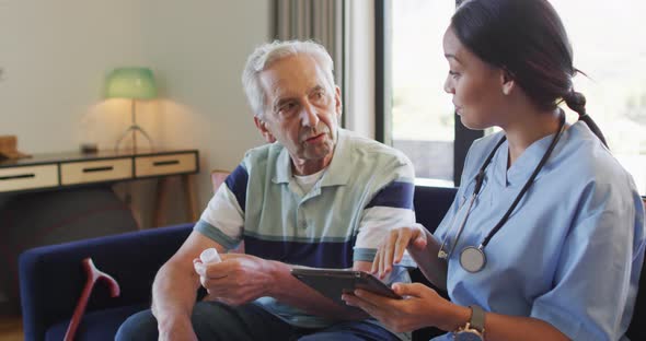 Animation of happy biracial female doctor talking about medicines with caucasian senior man