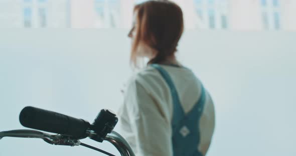 Shot from behind of a woman using a smartphone and headset at home