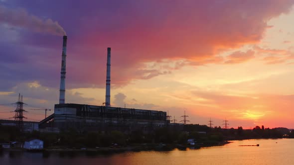 Manufacturing at sunset. Industrial factory near the river on the beautiful colorful background