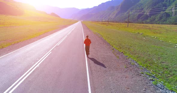 Low Altitude Flight in Front of Sporty Man at Perfect Asphalt Road