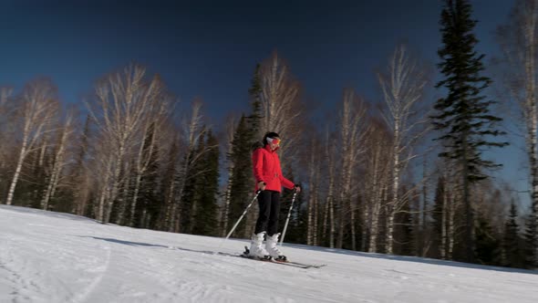 Elegant Woman Skiing Down The Slope Towards Sun In Winter In Mountains Resort