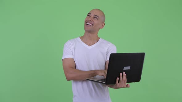 Happy Handsome Bald Man Thinking While Using Laptop