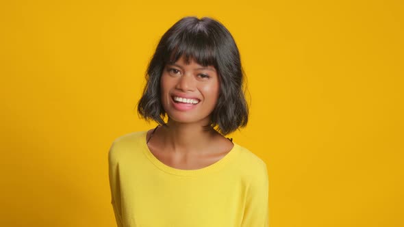 Optimistic Dark Skinned Young Woman Laughs Out Loudly on Yellow Background