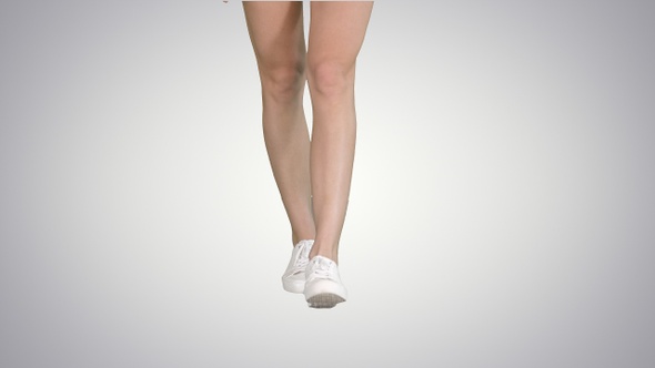 Female legs in gradient sneakers walking on gradient background.