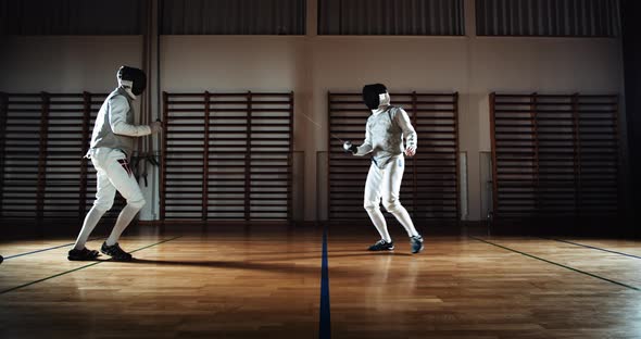 Two Men In Fencing Gear Duelling With Foils