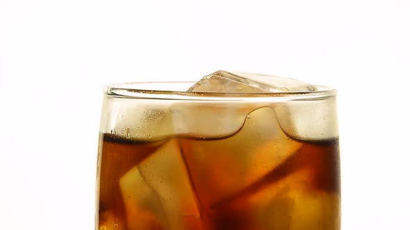 Glass of cola with ice cubes over white background