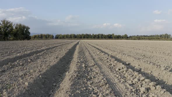 Plowed field slide drone shot, ground in the sun ready for seeding