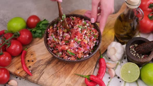 Woman Mixing Salsa Dip Sauce Ingredients in Wooden Bowl