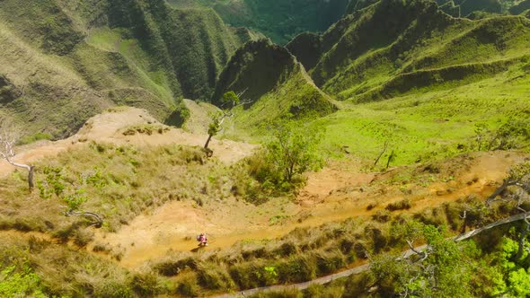 Aerial Epic Shot of Woman Hiking on the Edge of Green Jungle Mountain Landscape