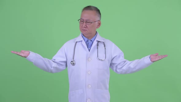 Serious Mature Japanese Man Doctor Comparing Something