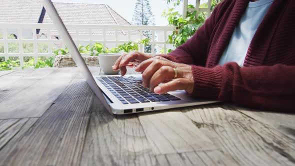 Midsection of senior mixed race woman using laptop outside