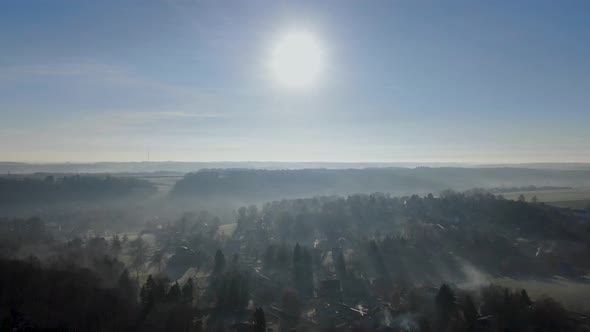 Aerial View of Forest and Farmland During Foggy and Cold Winter Morning with Blue Sky Facing the Sun