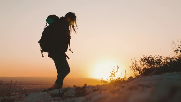 Woman Traveler with Backpack Hiking in Mountains. Silhouette Hiker Walking in the Mountains, Freedom