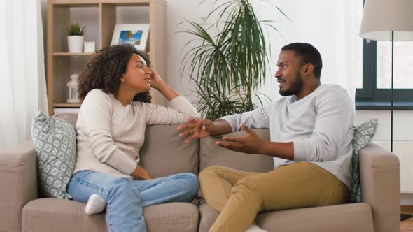 Happy Couple Sitting on Sofa and Talking at Home