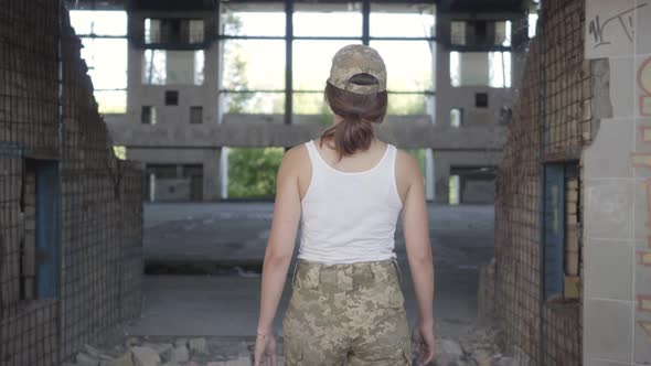 Attractive Young Woman in Military Uniform Walking Slowly in Dusty Dirty Abandoned Building