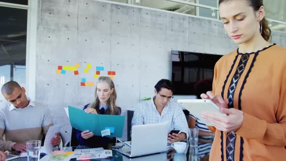 Woman using tablet while her colleagues sitting in background 4k