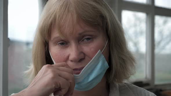 Portrait Of Mature Tired Caucasian Woman In Medical Mask On Her Face At Window