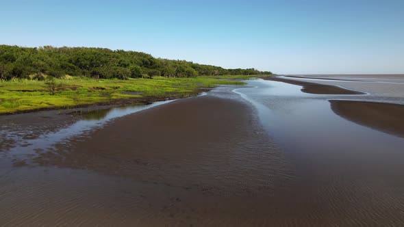 Aerial pull out shot capturing the pristine El Destino natural reserve sandy riverbank and coastal w