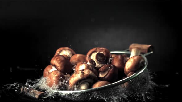 Super Slow Motion of the Colander with Mushrooms Falls on the Water with Splashes