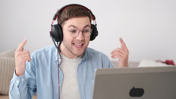 Cheerful Young Guy in Headphones Having Video Conferevce at Home