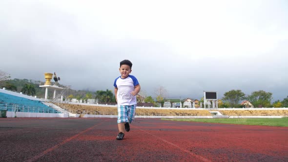 Asian Little Boy Running At Stadium alt