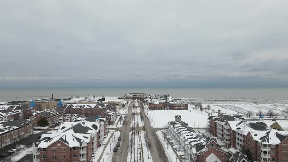 Aerial view toward Lake Michigan with housing and marina. Snow covered park. Cloudy sky.