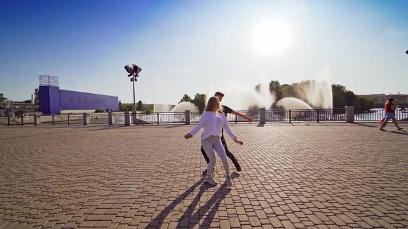 Man and woman dancing outdoors. Young couple moving synchronously in the street. 