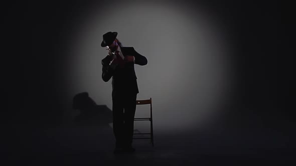 Elegant Man in a Black Hat Is Dancing an Erotic Dance. Spotlight on a Black Background. Close Up