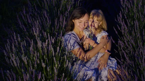 Mother and Girl Daughter Kid Kissing Laughing in Aromatic Flowers Lavender Field Garden at Night