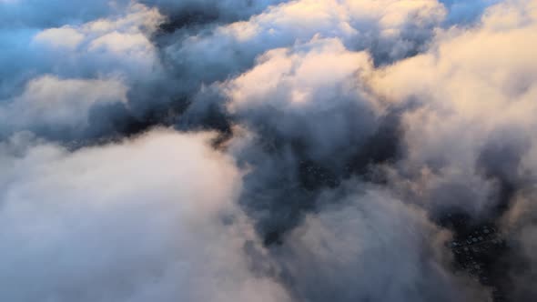 Aerial View From High Altitude of Distant City Covered with Puffy Cumulus Clouds Flying By Before